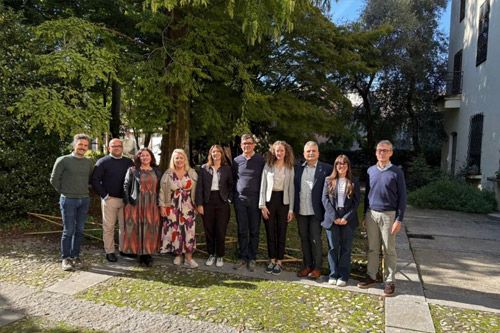 A group of ten people posing together in a sunny garden.